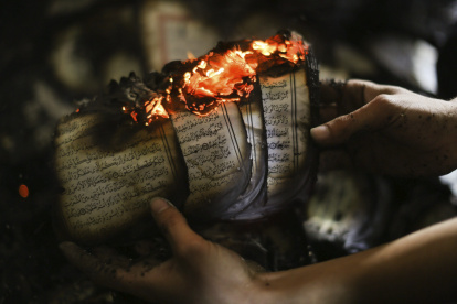 Panorama. Un hombre muestra un ejemplar del Corán en llamas en una mezquita que fue incendiada en Cisjordania en noviembre de 2014.