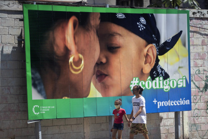 Un hombre y su hija pasan caminando frente a una valla que hace parte de la campaña por el SÍ en el referendo sobre el código de familia, hoy en La Habana (CUBA).
