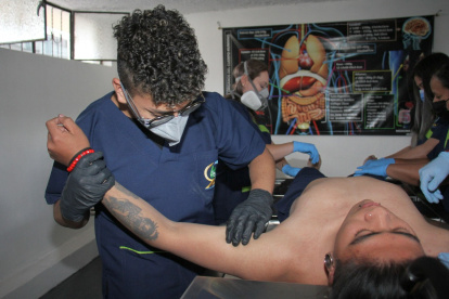 Trabajo. Uno de los estudiantes de Ortiz aprende a reconocer la anatomía y cómo manejar un cuerpo, que en este caso es otro estudiante que simula estar muerto.