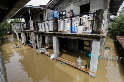 Una madre y su bebé observan desde la terraza de su vivienda completamente rodeada por el agua que anega la ciudad de San Miguel como consecuencia de las inundaciones provocadas por el tifón Noru en Filipinas. Al menos cinco personas perecieron este lunes y más de 74.000 fueron evacuadas por el paso del tifón, que tocó tierra en el noreste del archipiélago filipino con vientos de hasta 185 kilómetros por hora y que ya ha abandonado la isla de Luzón en dirección oeste. EFE/ Rolex Dela Pena