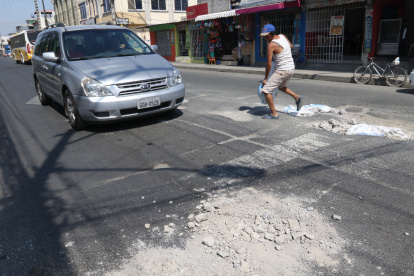 Andrés Romero coloca material de construcción en los huecos que se han formado en la avenida Laurice Anton. Una labor que realiza cada cuatro días.