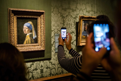 Visitantes toman fotografías de la "Niña de la Perla", del artista holandés Johannes Vermeer, en el Museo Mauritshuis de La Haya, en Países Bajos.