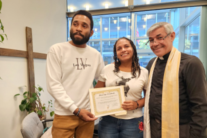 Los migrantes venezolanos Yonaiker Brujo y Nathalie Quintana muestran el certificado de matrimonio junto al sacerdote luterano, el padre Fabián Arias, en la iglesia San Pedro en Manhattan, Nueva York.
