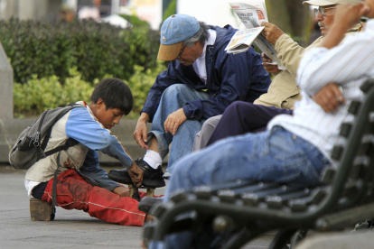 Fotografía de archivo en la que se registró a un niño al trabajar lustrando zapatos en una calle de Quito (Ecuador).