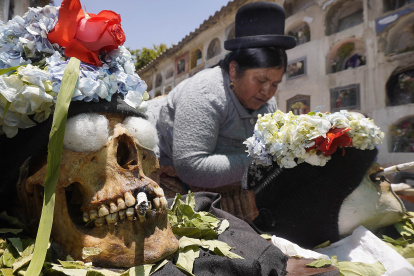 Una persona rinde culto a las denominadas "ñatitas" o cráneos humanos, con un cigarrillo y flores hoy, en un cementerio en La Paz (Bolivia). El Cementerio General de La Paz se llenó este martes de "ñatitas", los cráneos humanos a los que se le rinde culto en Bolivia con flores, coca y velas para agradecerles y pedirles favores como salud, justicia y trabajo. Como cada 8 de noviembre, el día de las "ñatitas", calaveras humanas que tienen ese nombre porque les falta la nariz, llegan al cementerio acompañados de sus dueños que las trasladan en especies de urnas transparentes para que sean bendecidas. EFE/ Javier Mamani.