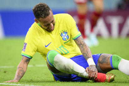 Neymar, seleccionado brasileño, se toma si tobillo lesionado, en el partido ante Serbia.