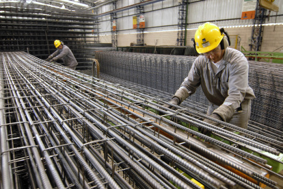 Fábrica.- Los trabajadores construyen columnas de barras de refuerzo en una planta.