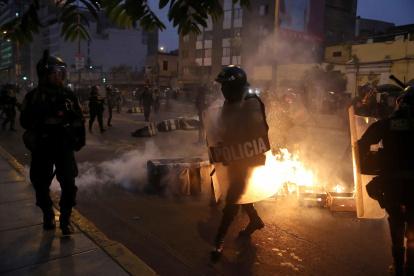 Miembros de la policía vigilan a cientos de manifestantes a favor de Pedro Castillo y en contra del Congreso que se manifiestan en las calles del centro, en Lima (Perú).