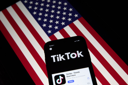 Fotografía de archivo que muestra la aplicación TikTok en la pantalla de un teléfono celular, con la bandera estadounidense de fondo.