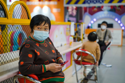 Una mujer protegida con una mascarilla utiliza su móvil en un centro comercial de Pekín este 11 de enero. EFE/EPA/WU HAO