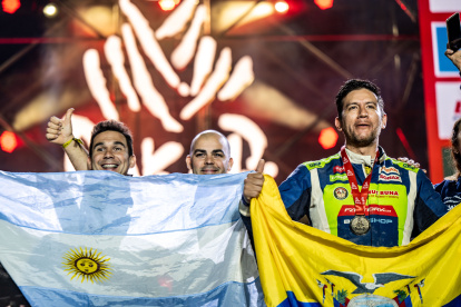 El piloto Sebastián Guayasamín (d) y su celebración con la bandera ecuatoriana tras concluir el rally Dakar.