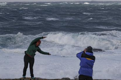 Los turistas observan el fuerte oleaje esta tarde en la costa de Muxía, en la Costa de la Muerte. Tras el paso ayer lunes de la borrasca Gérard, la parte más adversa de este temporal invernal corresponderá a la borrasca Fien, que a partir de este martes mantiene activado el aviso rojo en Galicia por olas de 9 metros y en otras 12 comunidades en naranja por nieve en cotas bajas, lluvias y fuerte viento. EFE/Lavandeira jr