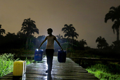 Los comuneros a oscuras van en busca de sus baldes llenos de agua por la lluvia