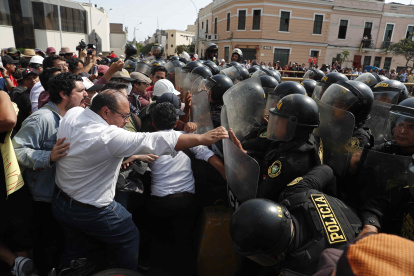 Policías chocan con ciudadanos junto a la sede de la Prefectura, donde se encuentran los manifestantes detenidos, en Lima