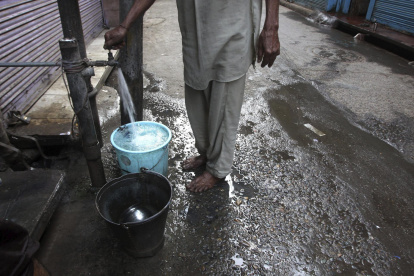 Un hombre llena unos cubos de agua en una fuente en un mercado en Amritsar (India), en una fotografía de archivo.