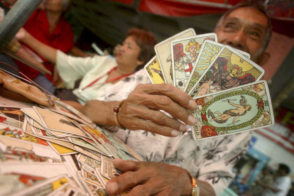 Un filipino, echador de cartas del Tarot para adivinar el destino de los transeúntes, en Manila. La cartomancia es una de las mancias adivinatorias.