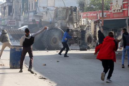 Palestinos lanzan piedras en medio de enfrentamientos con tropas israelíes durante una incursión en Yenín, Cisjordania, este 26 de enero.