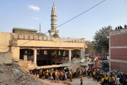 Trabajadores de los servicios de emergencia buscan posibles victimas entre los escombros de una mezquita de Peshawar en la que un atentado suicida a la hora del rezo ha matado al menos a 32 policías.