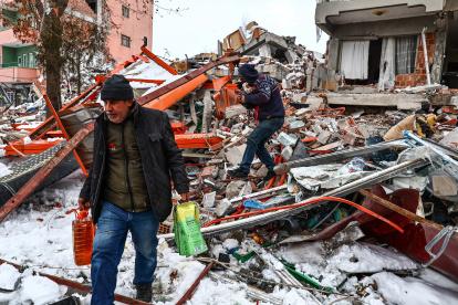 Personas transportan alimentos rescatados de un edificio derrumbado tras un fuerte terremoto en el distrito de Elbistan de Kahramanmaras, sureste de Turquía, el 07 de febrero de 2023