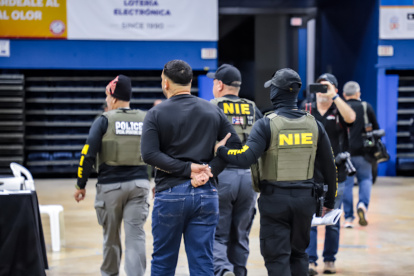 Varios  agentes mientras acompañan a una de las personas arrestadas durante un operativo