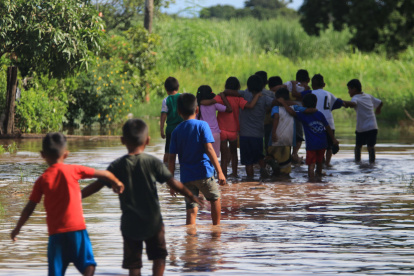 Unos niños caminan en medio de una inundación en la comunidad Rancho Chico perteneciente al municipio de Okinawa