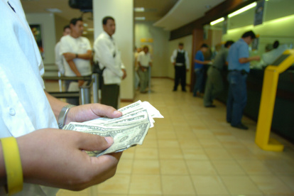 Dinero.- Una persona cuenta los dólares que ha recibido en un banco.