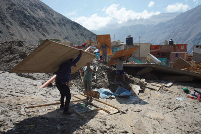 Personas caminan entre los escombros ocasionados por el alud en el pueblo de Secocha en Arequipa (Perú).