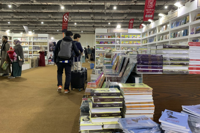 Pistas. Jóvenes en maletas llevan libros comprados en feria de El Cairo.