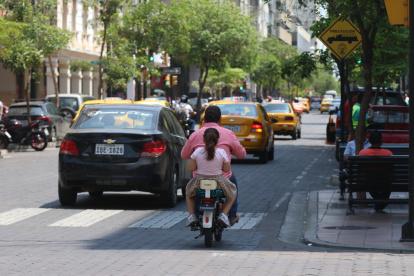 Motorizado en la 9 de Octubre conduce en una bicicleta eléctrica con una menor como acompañante, ambos sin casco de protección.
