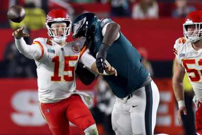 El mariscal de campo de los Kansas City Chiefs, Patrick Mahomes (izq.), pasa bajo la presión del tackle defensivo de los Philadelphia Eagles, Jordan Davis (der.).