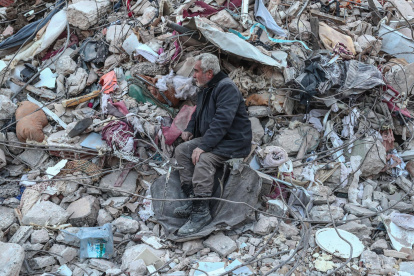 Un hombre se sienta sobre los escombros mientras espera noticias de su familia en el sitio de los edificios derrumbados después de un fuerte terremoto, en Hatay, Turquía, el 15 de febrero de 2023.