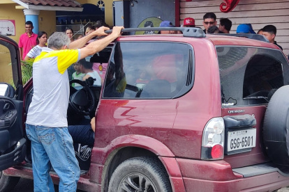 Allegados y curiosos observan el cadáver de un hombre baleado dentro de su vehículo.