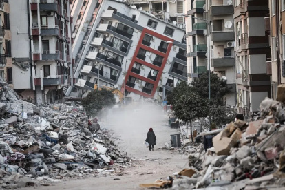 Una mujer pasa junto a edificios en ruinas, tras los terremotos de Turquía.