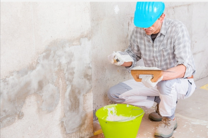 Obra. Un maestro de construcción arregla una pared que tiene humedad.