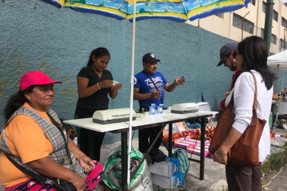 Una postal tradicional del día de elecciones. Personas ofrecen emplasticar el certificado de votación.