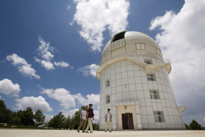 Tres personas caminan frente al observatorio Gaomeigu, fuera de Lijiang al suroeste de la provincia china de Yunnan, uno de los mayores del este de Asia .