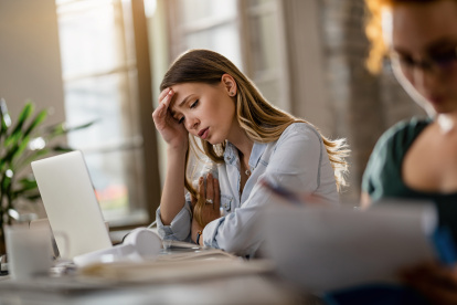 Young displeased businesswoman having a headache while working in the office.