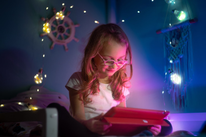 girl with glasses plays with tablet at night
