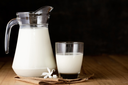 milk in glass and jug on wooden table on black background