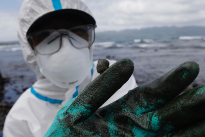 Un pescador con un traje protector muestra el vertido de petróleo que asola las costas de Pola, en la isla de Mindoro, Filipinas este lunes. Las autoridades filipinas temen que el vertido tóxico, que ya ha llegado varias islas del centro del archipiélago tras el hundimiento de un carguero el pasado martes, pueda afectar a la isla de Boracay, el destino turístico más importante del país. EFE/ Francis R. Malasig