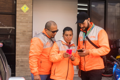 Trabajadores.- Tres personas revisan la aplicación de delivery con la que laboran.