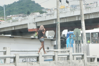 Un mujer camina sobre el tubo de un puente en el norte de la ciudad.