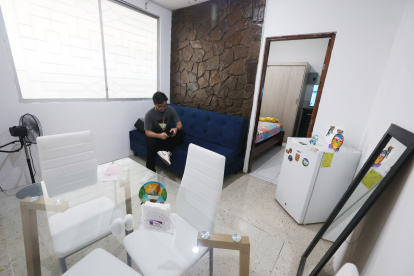 Departamento. Una persona está en su sala - comedor, que se ve pequeña, así como el dormitorio.