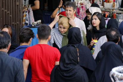 Una mujer se ajusta el velo, mientras camina por una calle