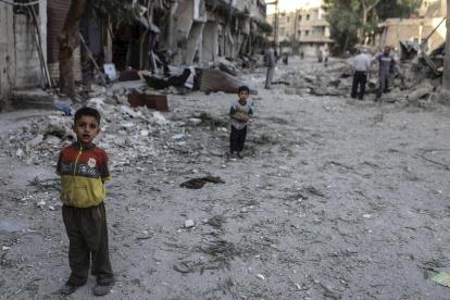 Imagen de archivo de niños delante de viviendas destruídas por bombardeos en Arbin, a las afueras de Damasco (Siria). EFE/Mohammed Badra