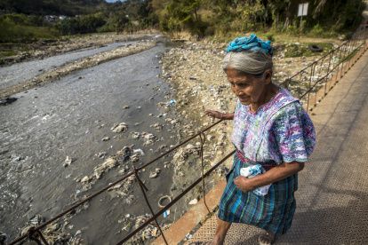 Una mujer cruza el río Las Vacas que transporta cientos de toneladas de basura, el 13 de febrero 2023, provenientes de la Ciudad de Guatemala, en Chinautla (Guatemala).