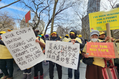 Decenas de vendedores ambulantes, de diversos grupos étnicos, sostienen carteles en varios idiomas con sus demandas durante una protesta relizada hoy frente a la Alcaldía de Nueva York.