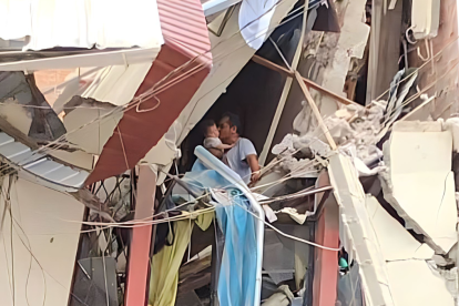 Escenario. Es un hombre, aferradose a lo que queda de una pared y con los pies sobre una casa a punto de derrumbarse, pero quien se muestra feliz de que la vida que carga en sus brazos esté intacta.