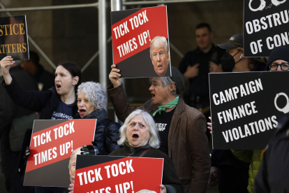 Manifestantes gritan y sostienen carteles frente al Tribunal Penal de Nueva York antes de una posible acusación contra el expresidente Donald Trump en Nueva York, Nueva York.