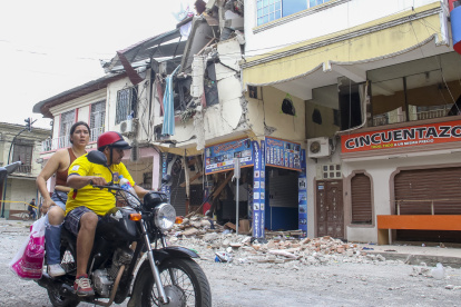 AME3860. PASAJE (ECUADOR), 19/03/2023.- Una pareja en motocicleta pasa hoy, frente a una edificación afectada por un terremoto de magnitud 6,5 en la ciudad de Pasaje (Ecuador). A 446 ascendió la cifra de heridos por el sismo de magnitud 6,5 en la escala abierta de Richter, que se registró el sábado en la provincia del Guayas, en la zona costera de Ecuador, y que dejó 14 fallecidos. EFE/Jhonatan Miranda